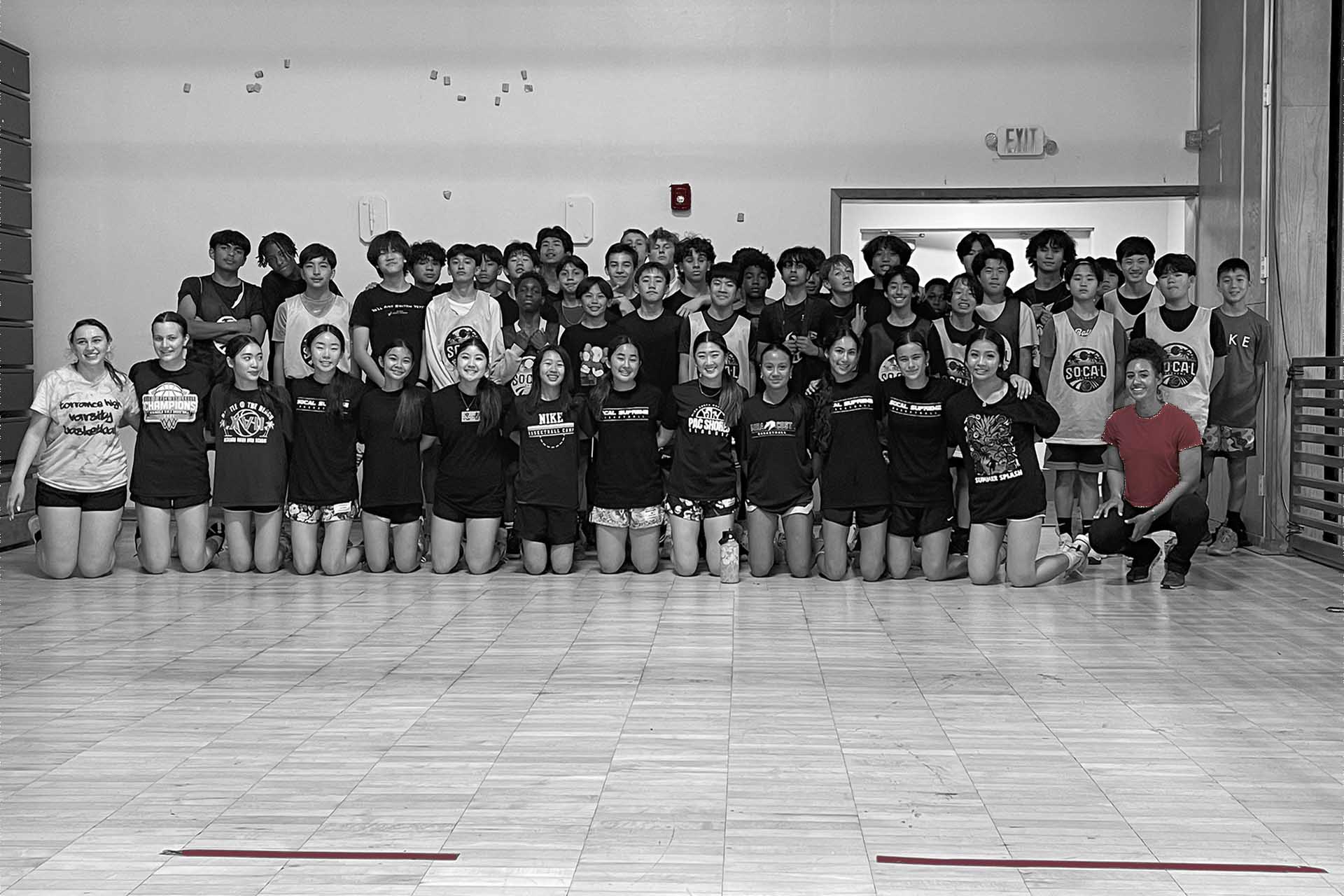 Group of athletes and coaches posing together in a gym after training.