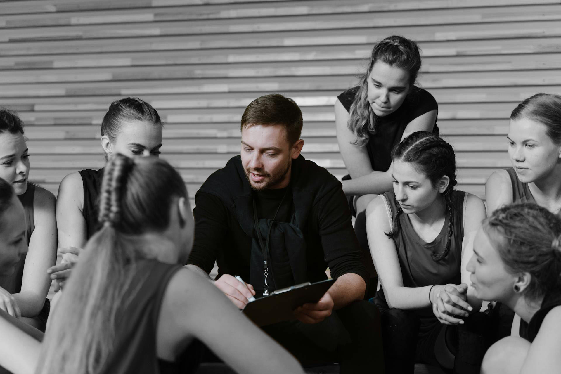 Coach discussing strategy with a group of athletes in a gym, emphasizing teamwork and guidance.